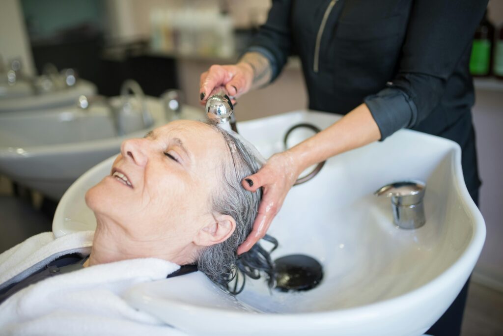 Elderly woman enjoying a soothing hair wash in a stylish Portuguese salon, capturing a tranquil moment.